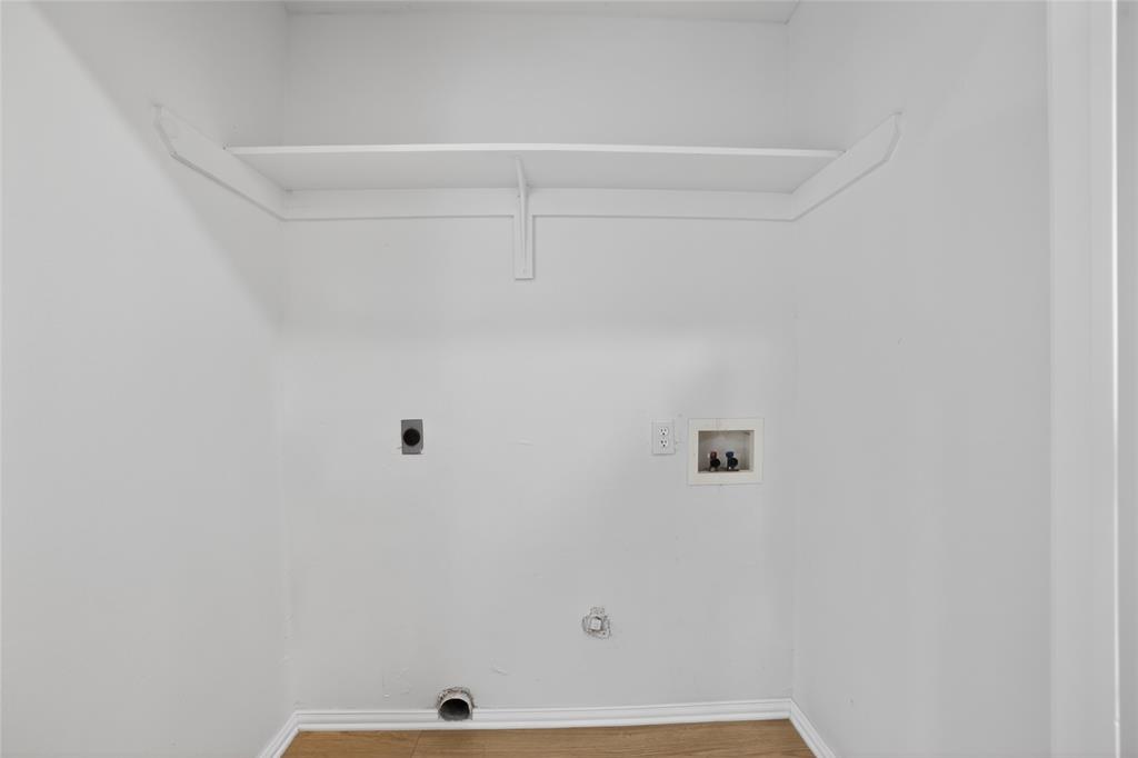 808 Park Street Commerce, TX 75428 - Photo 29 of 29 This utility area features light-colored walls, a built-in shelf, and wood flooring