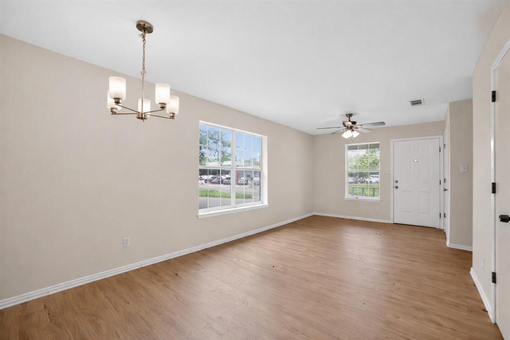 808 Park Street Commerce, TX 75428 - Photo 3 of 29 Spacious living area featuring light-colored walls, wood-look flooring, and a ceiling fan