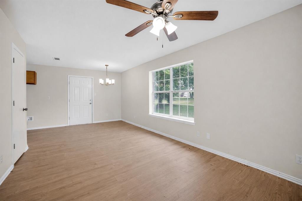 808 Park Street Commerce, TX 75428 - Photo 5 of 29 Spacious living area featuring light-colored walls, wood-look flooring, and a ceiling fan