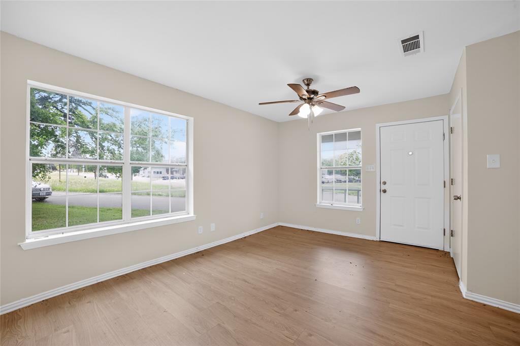 808 Park Street Commerce, TX 75428 - Photo 6 of 29 The property features warm-toned flooring, light-colored walls, and a ceiling fan with integrated lighting