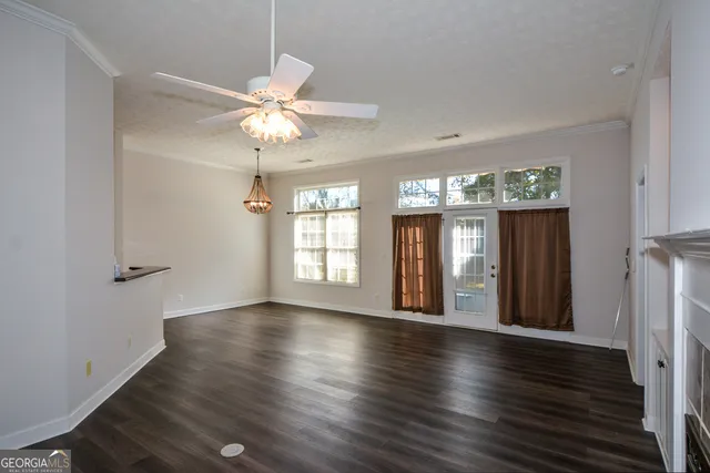 a view of an empty room with wooden floor fireplace and a window