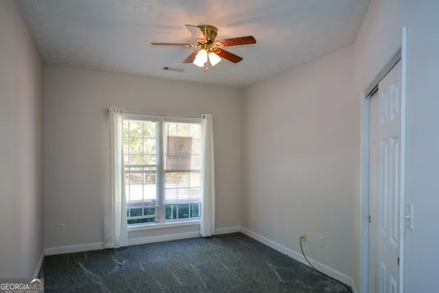 an empty room with a chandelier fan and windows