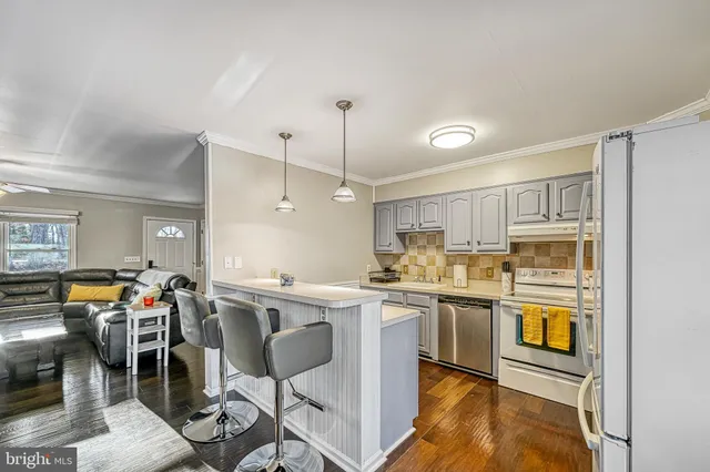 a kitchen with stainless steel appliances granite countertop a stove top oven a sink dishwasher and white cabinets with wooden floor