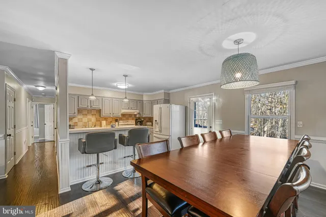 a dining room with wooden floor a chandelier a wooden table and chairs