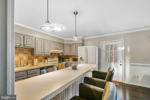 a kitchen with stainless steel appliances kitchen island granite countertop a refrigerator a stove and white cabinets with wooden floor