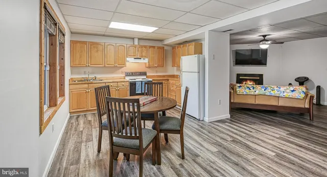 a kitchen with stainless steel appliances granite countertop a stove a refrigerator a microwave oven with a dining table and chairs with wooden floor