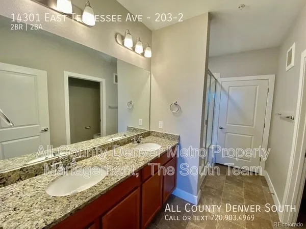 a bathroom with a granite countertop sink a mirror and a shower