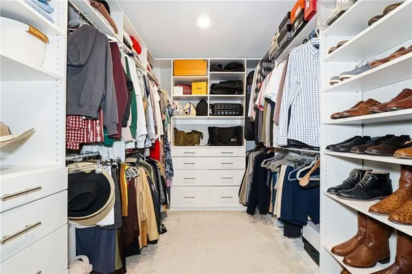 a view of walk in closet with clothes and shoes