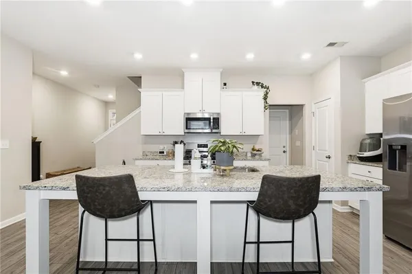 a kitchen with stainless steel appliances granite countertop a kitchen island a stove and a refrigerator with wooden floor