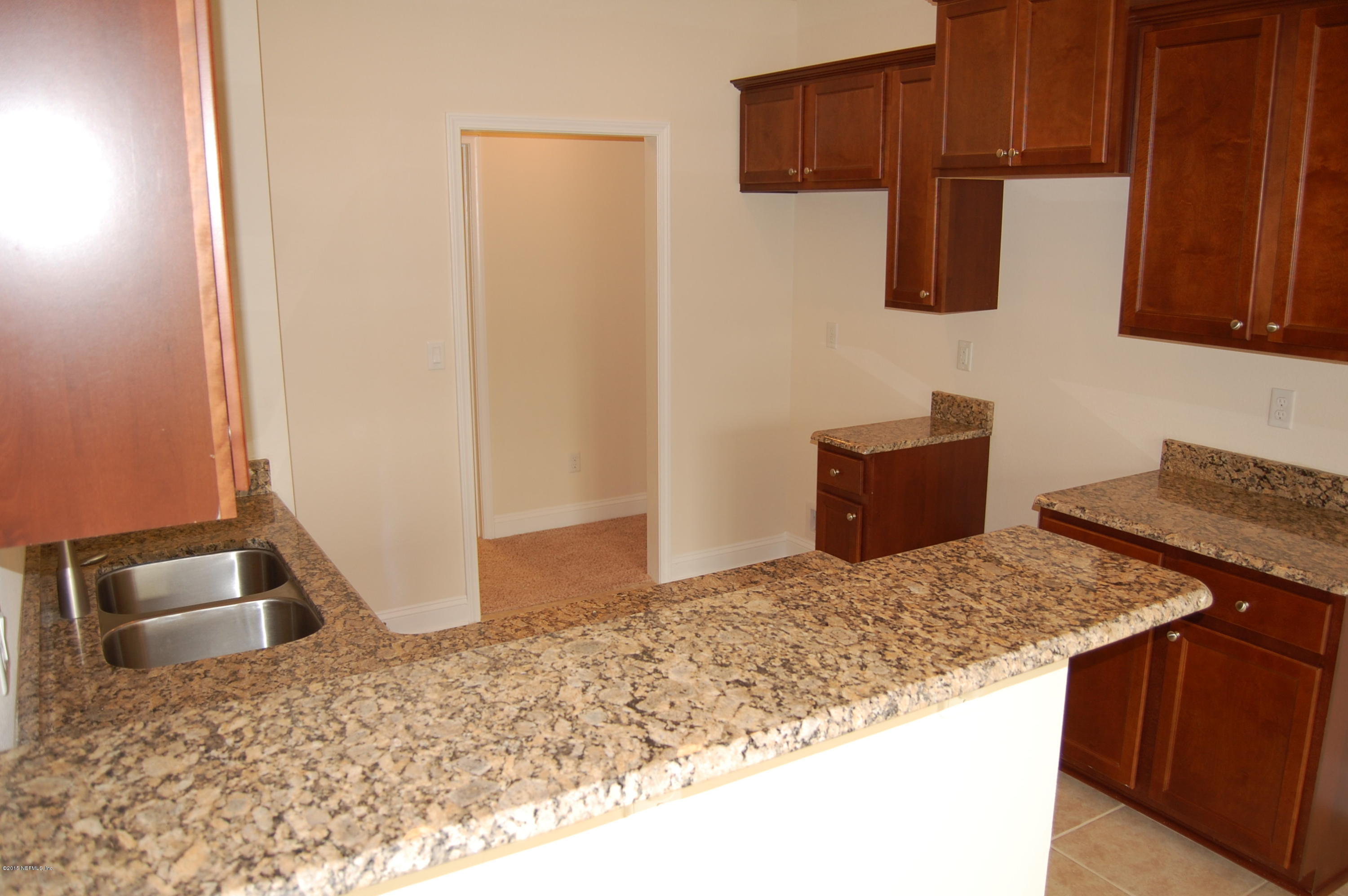 8000 Capeside Way Jacksonville, FL 32222 - Photo 14 of 32 a kitchen with granite countertop a sink a stove and a wooden cabinets