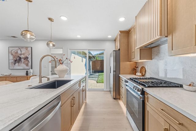 a kitchen with kitchen island stainless steel appliances a sink stove and cabinets