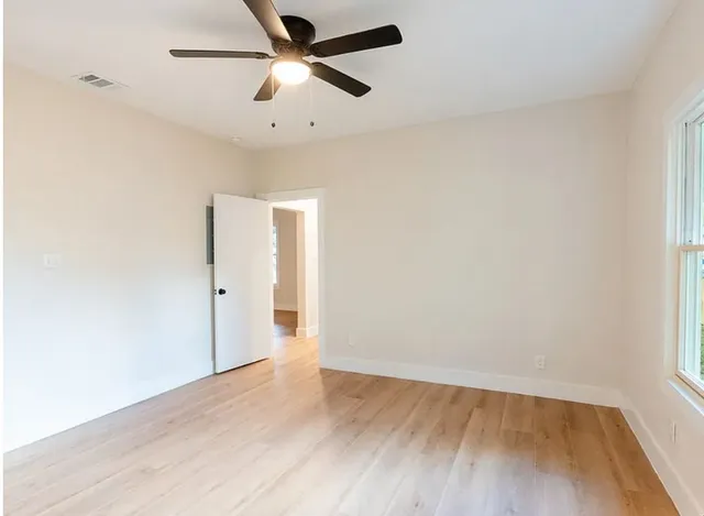 an empty room with wooden floor and windows