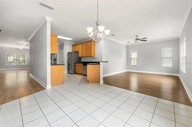 a view of a kitchen with kitchen island granite countertop a refrigerator a stove top oven and a dining table with wooden floor