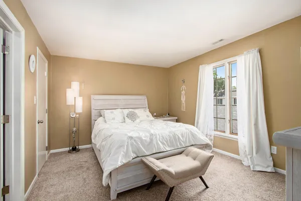 a bedroom with a bed and a chair with exposed radiator