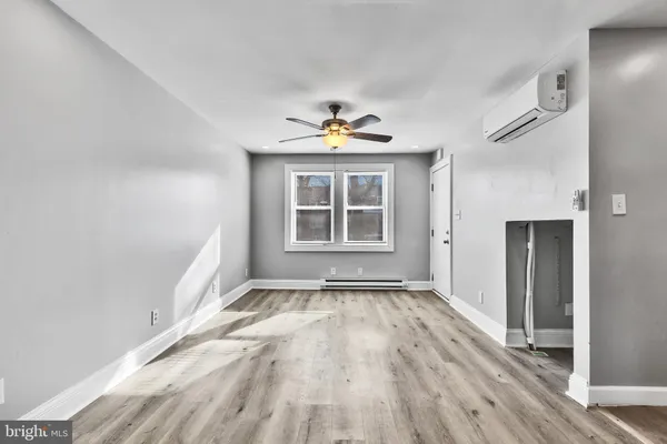 an empty room with wooden floor chandelier fan and windows