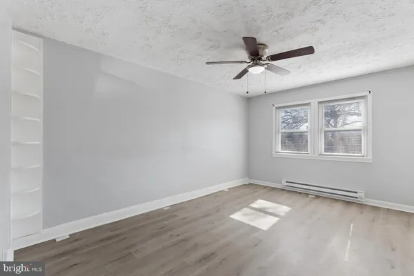 a view of a livingroom with a ceiling fan a kitchen space with wooden floor