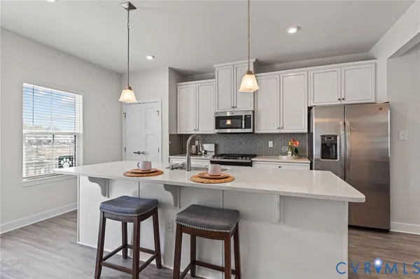 a kitchen with a sink a stove a refrigerator and white cabinets with wooden floor