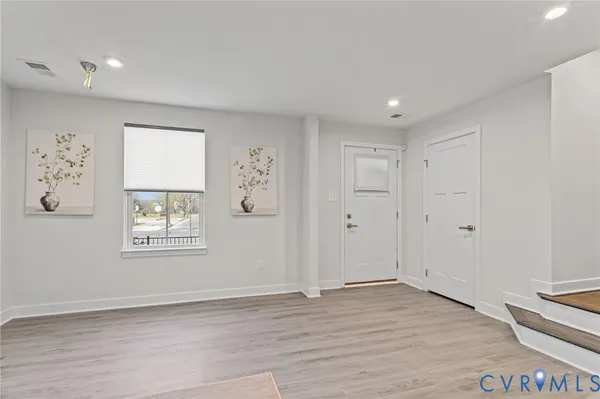 a view of an empty room with wooden floor and a window