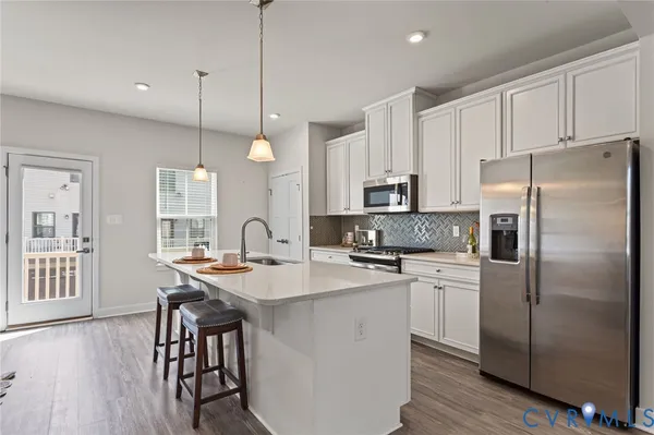 a kitchen with stainless steel appliances granite countertop a refrigerator a sink dishwasher a stove and white cabinets with wooden floor