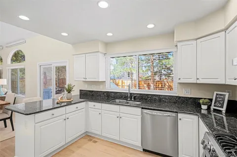 a kitchen with granite countertop a sink white cabinets and window