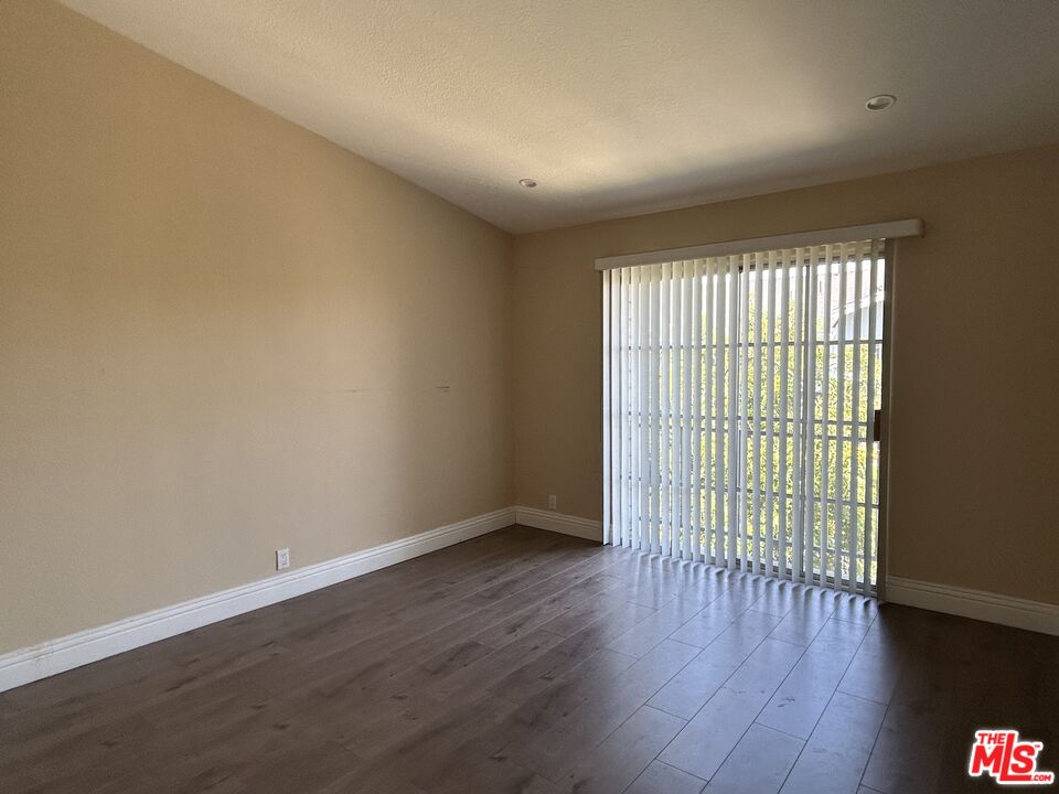 7430 Corbin Avenue, Unit 33 Reseda, CA 91335 - Photo 17 of 28 a view of an empty room with wooden floor and a window