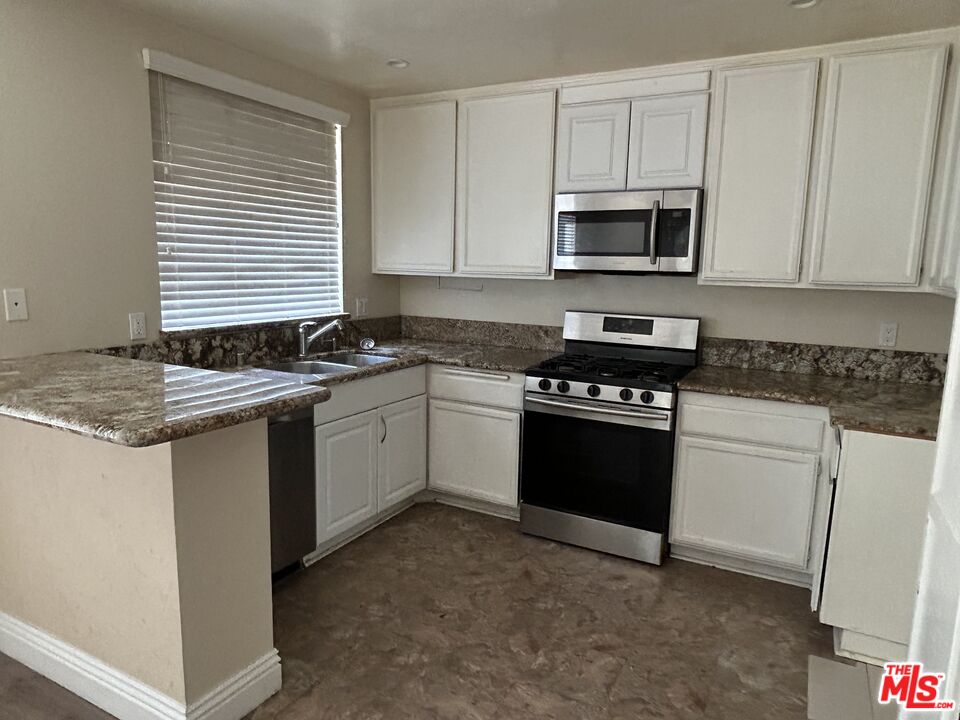 7430 Corbin Avenue, Unit 33 Reseda, CA 91335 - Photo 7 of 28 a white kitchen with granite countertop a stove top oven microwave and cabinets