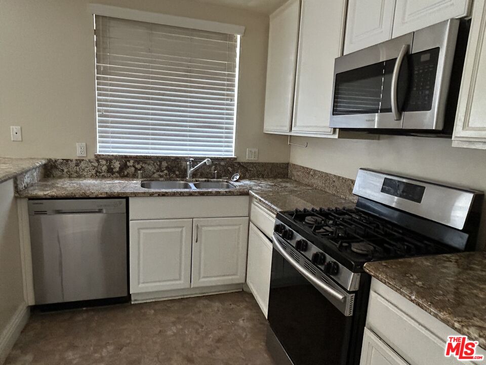 7430 Corbin Avenue, Unit 33 Reseda, CA 91335 - Photo 8 of 28 a kitchen with stainless steel appliances granite countertop a sink stove and microwave