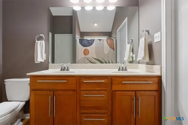 a bathroom with a sink a toilet a mirror and shower