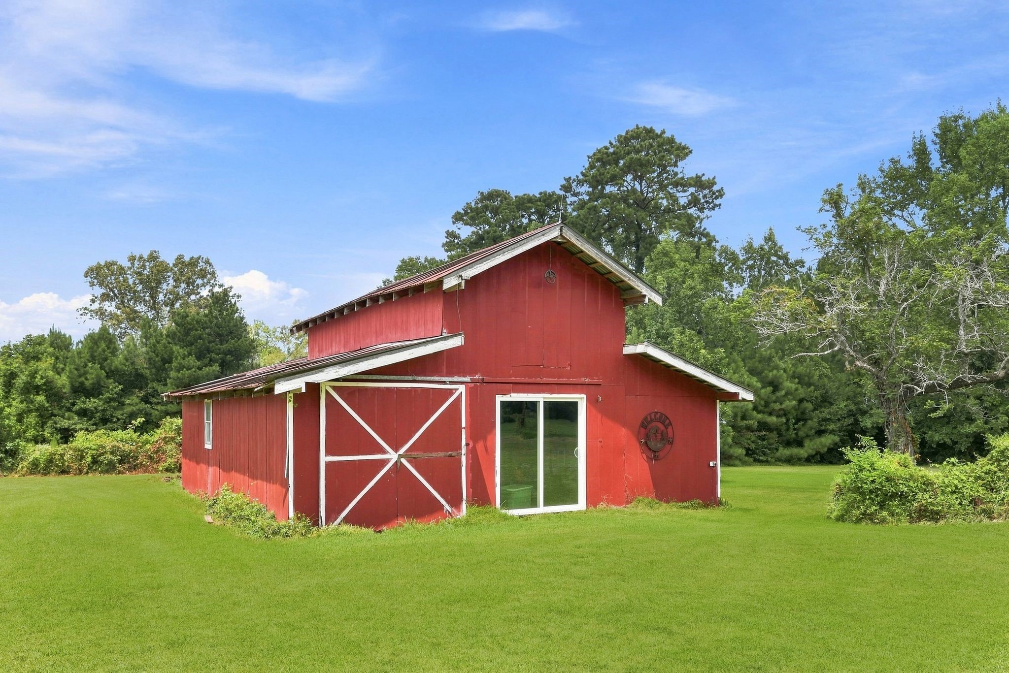 151 Parker Road New Waverly, TX 77358 - Photo 32 of 36 Charming red barn nestled in lush greenery, offering a rustic touch and ample space for storage or creative projects.