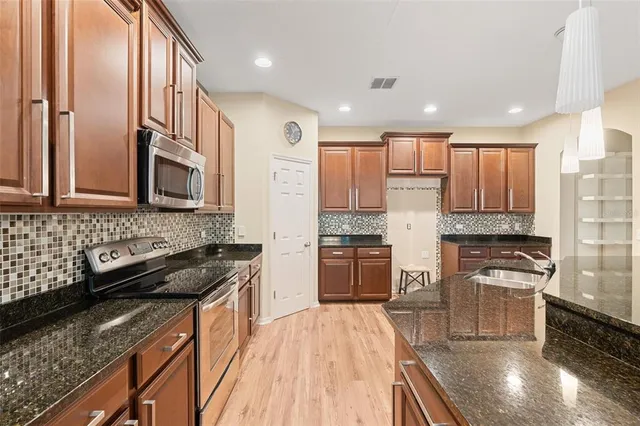 a open kitchen with stainless steel appliances kitchen island granite countertop a refrigerator a stove a sink dishwasher and a wooden cabinets