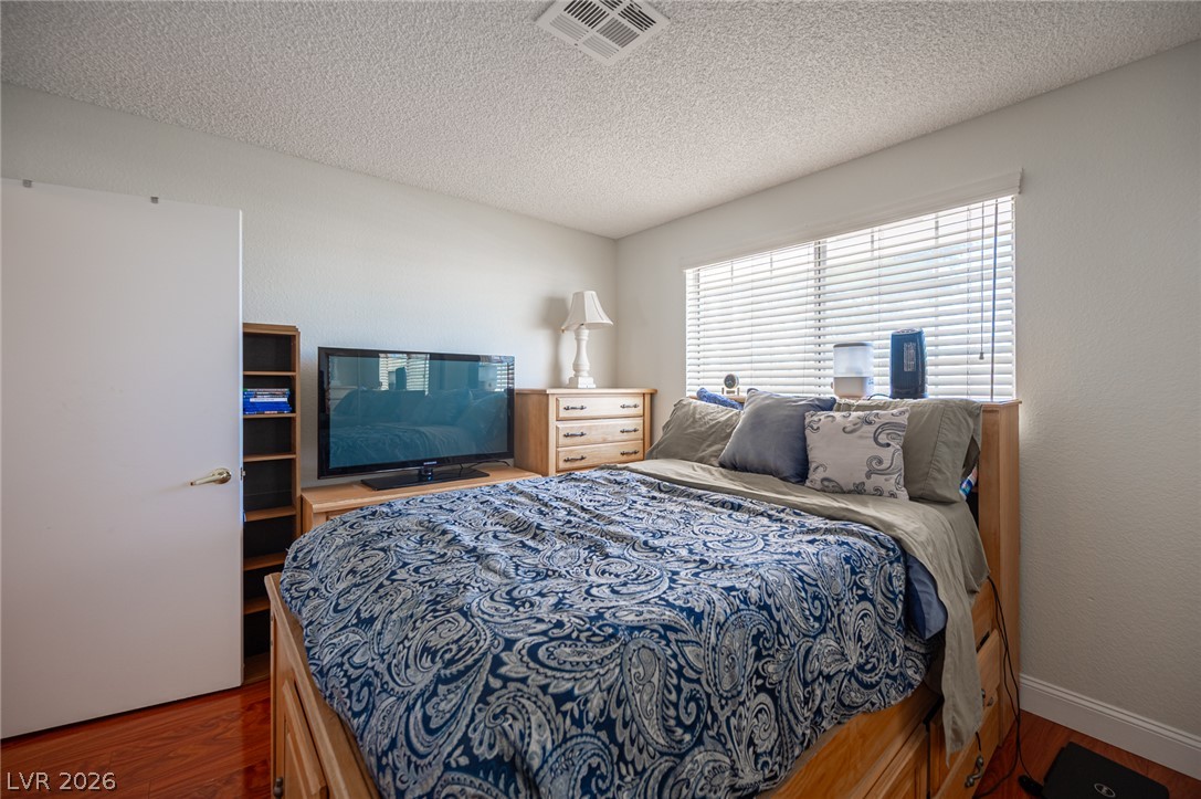 718 Rusty Spur Drive Henderson, NV 89014 - Photo 44 of 50 Wood flooring and natural light elevate this inviting bedroom retreat.