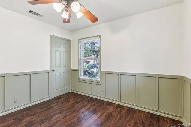 an empty room with wooden floor chandelier and windows