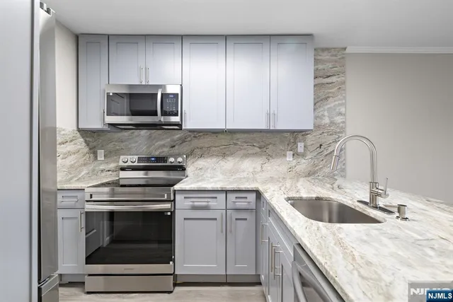 a view of a kitchen with kitchen island a sink wooden floor and black appliances