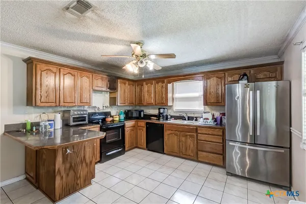a kitchen with stainless steel appliances granite countertop a stove top oven a refrigerator a sink a dining table and chairs