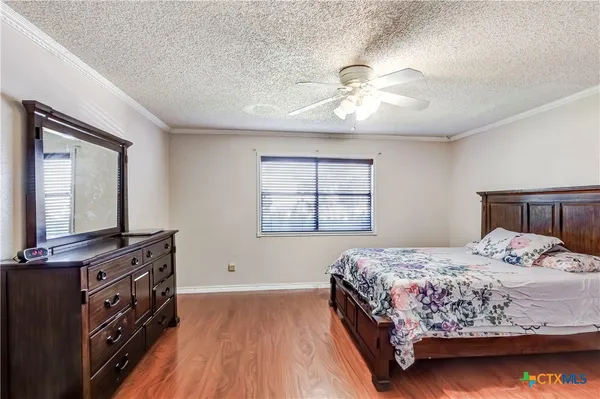 a bedroom with a bed and a flat tv screen on dresser
