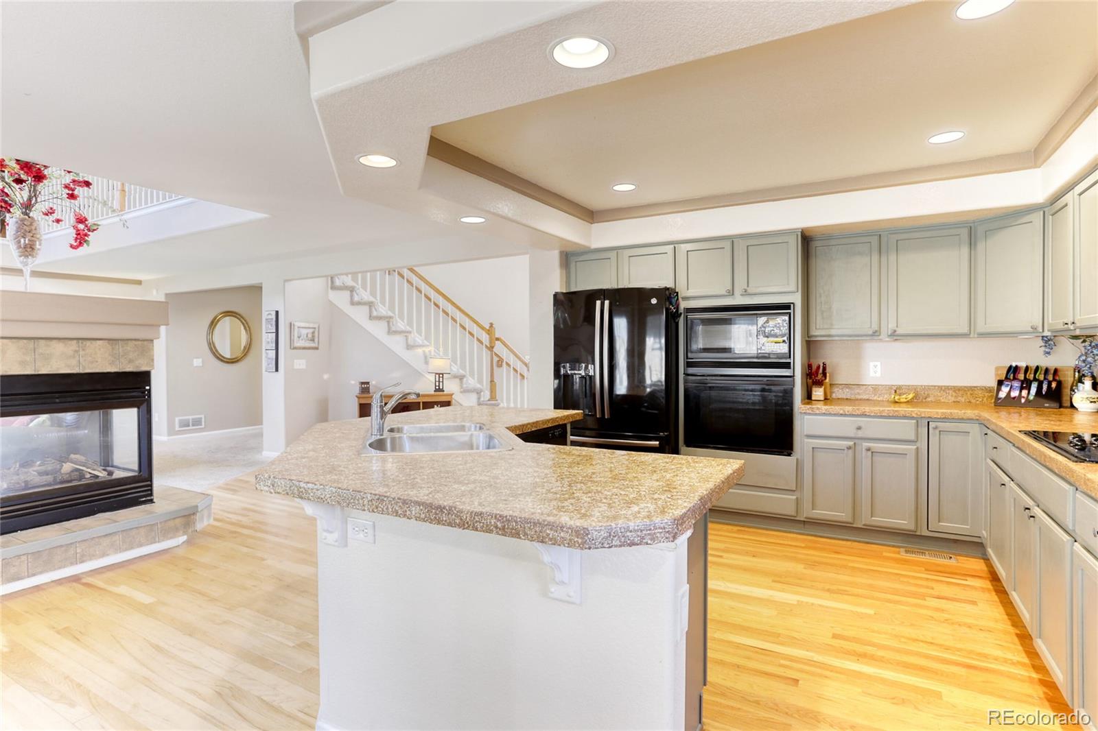 4425 Iran Street Denver, CO 80249 - Photo 10 of 36 a kitchen with stainless steel appliances granite countertop a sink and dishwasher a stove top oven with wooden floor