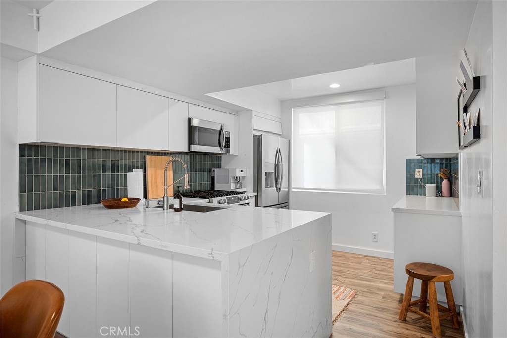 5435 Yarmouth Avenue, Unit 7 Encino, CA 91316 - Photo 9 of 31 a kitchen with stainless steel appliances a stove a sink a refrigerator a couch and a cabinets