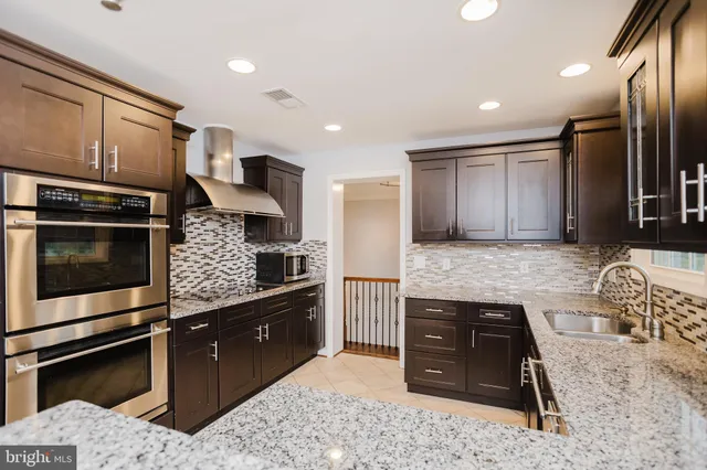 a kitchen with stainless steel appliances kitchen island granite countertop a stove a sink and a microwave
