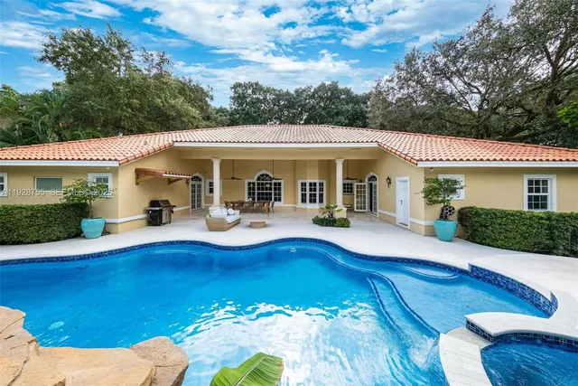 a view of a white house with swimming pool lawn chairs and a fire pit