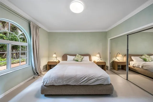 a bed sitting in a spacious bedroom next to a window