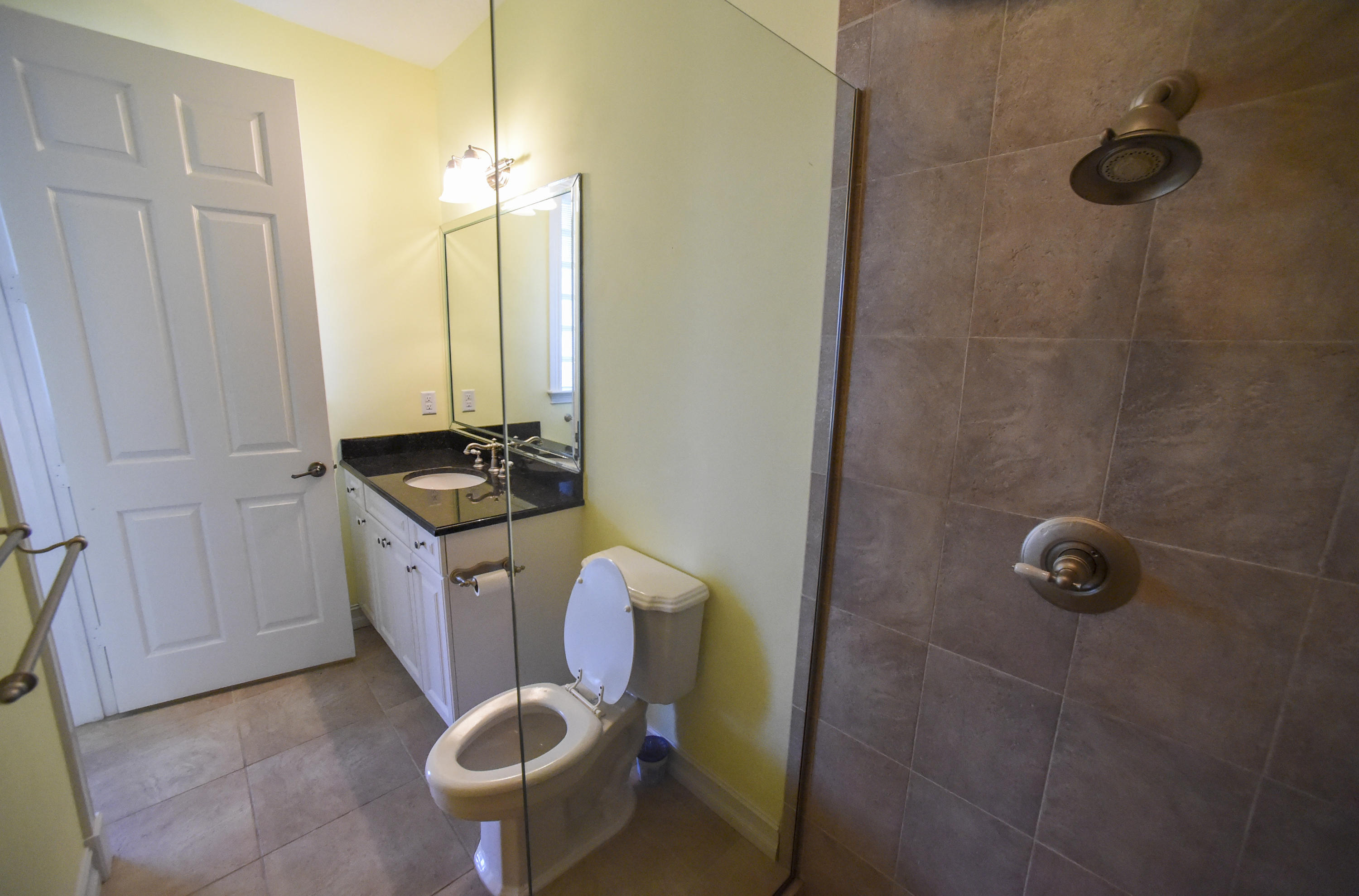 552 Southwest St Lucie Crescent Stuart, FL 34994 - Photo 22 of 36 a bathroom with a granite countertop sink a toilet a mirror and shower