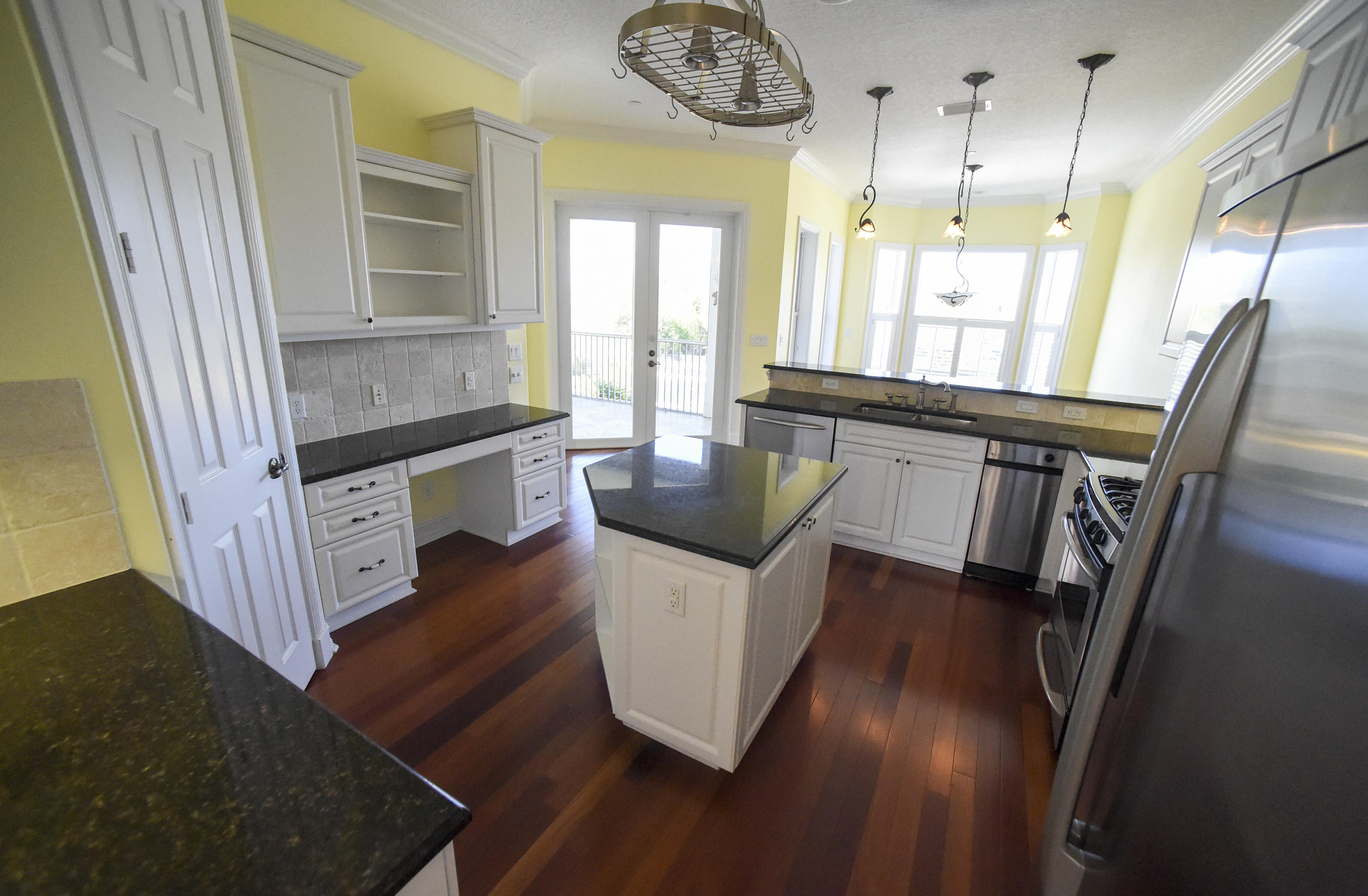 552 Southwest St Lucie Crescent Stuart, FL 34994 - Photo 9 of 36 a kitchen with stainless steel appliances granite countertop a stove a refrigerator a sink a dining table and chairs with wooden floor