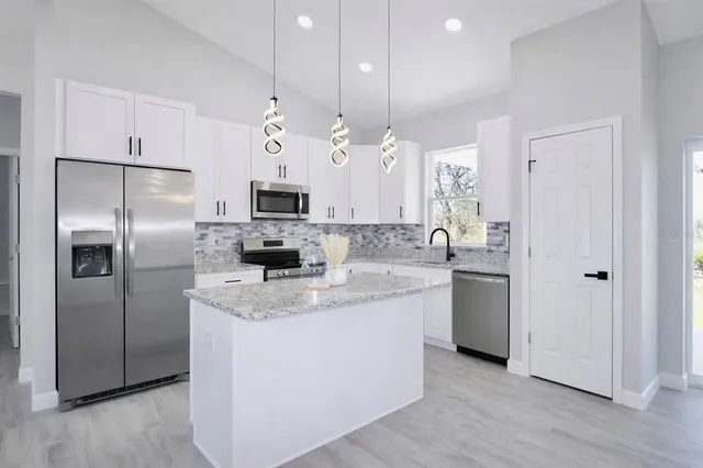 a kitchen with kitchen island a counter top space stainless steel appliances and a window