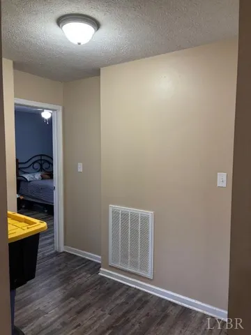 an empty room with wooden floor and bathroom view