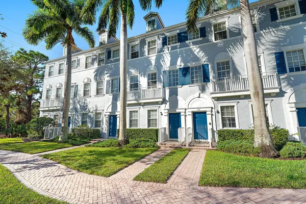 a view of a white building among the yard with palm trees