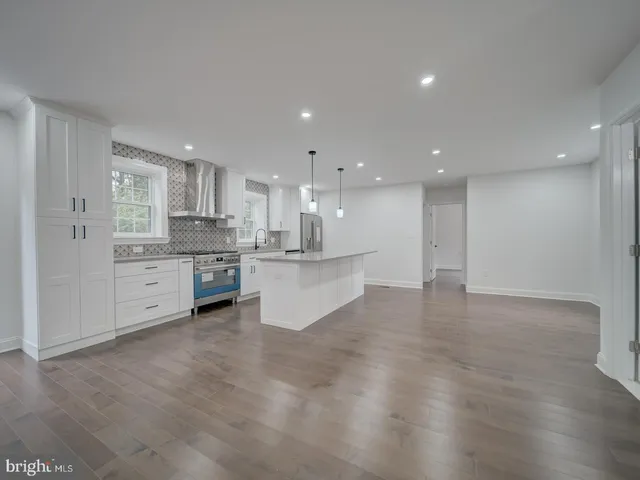 a view of an empty room with wooden floor and a ceiling fan