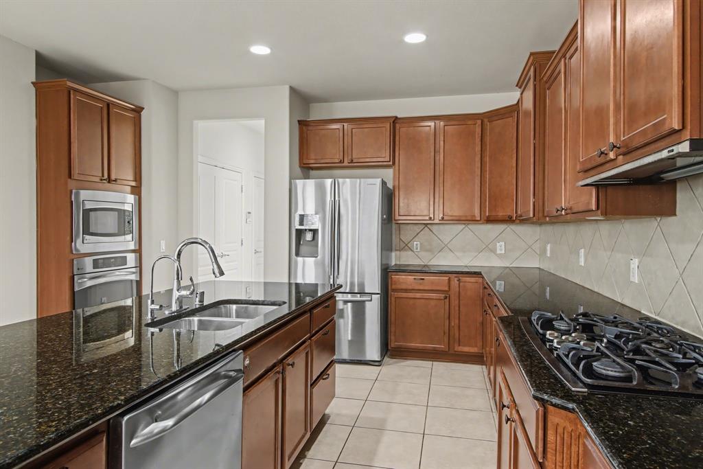 6131 Myrtle Lane Frisco, TX 75036 - Photo 13 of 34 a kitchen with granite countertop stainless steel appliances a sink stove and refrigerator
