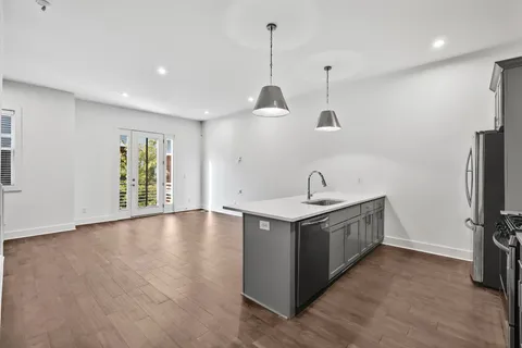 a view of a kitchen sink a refrigerator and wooden floor