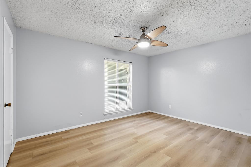 4211 Holland Avenue, Unit 105 Dallas, TX 75219 - Photo 16 of 26 an empty room with wooden floor fan and windows