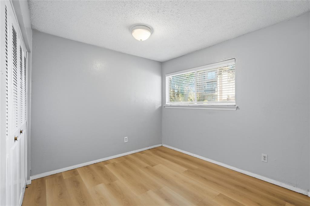 4211 Holland Avenue, Unit 105 Dallas, TX 75219 - Photo 19 of 26 a view of an empty room with wooden floor and a window